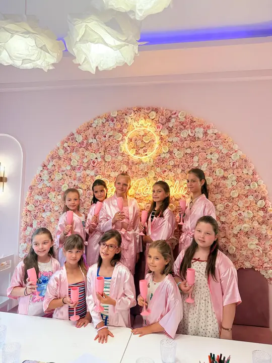 The princesses of a party, in front of the Regatul Răsfățului neon sign