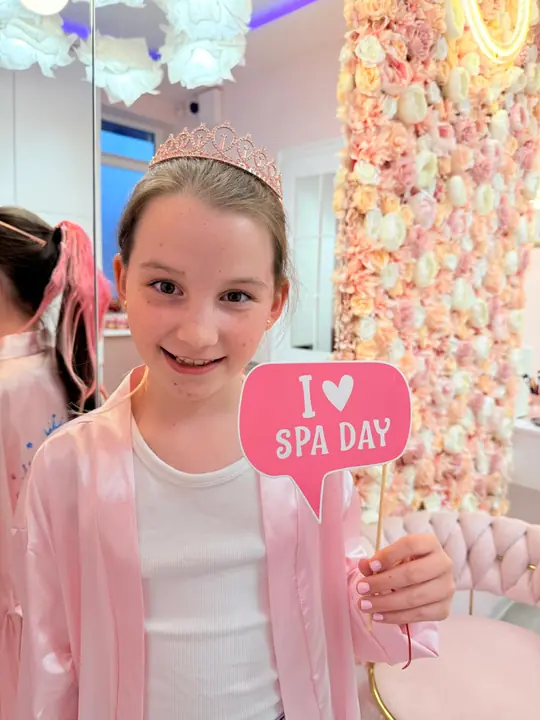 A princess with a tiara and an I love spa day sign